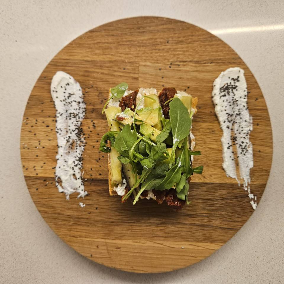 Tosta de queso ricotta, tomate seco, tiras de berenjena, aguacate y rúcula Tosta de queso ricotta, tomate seco, tiras de berenjena, aguacate y rúcula