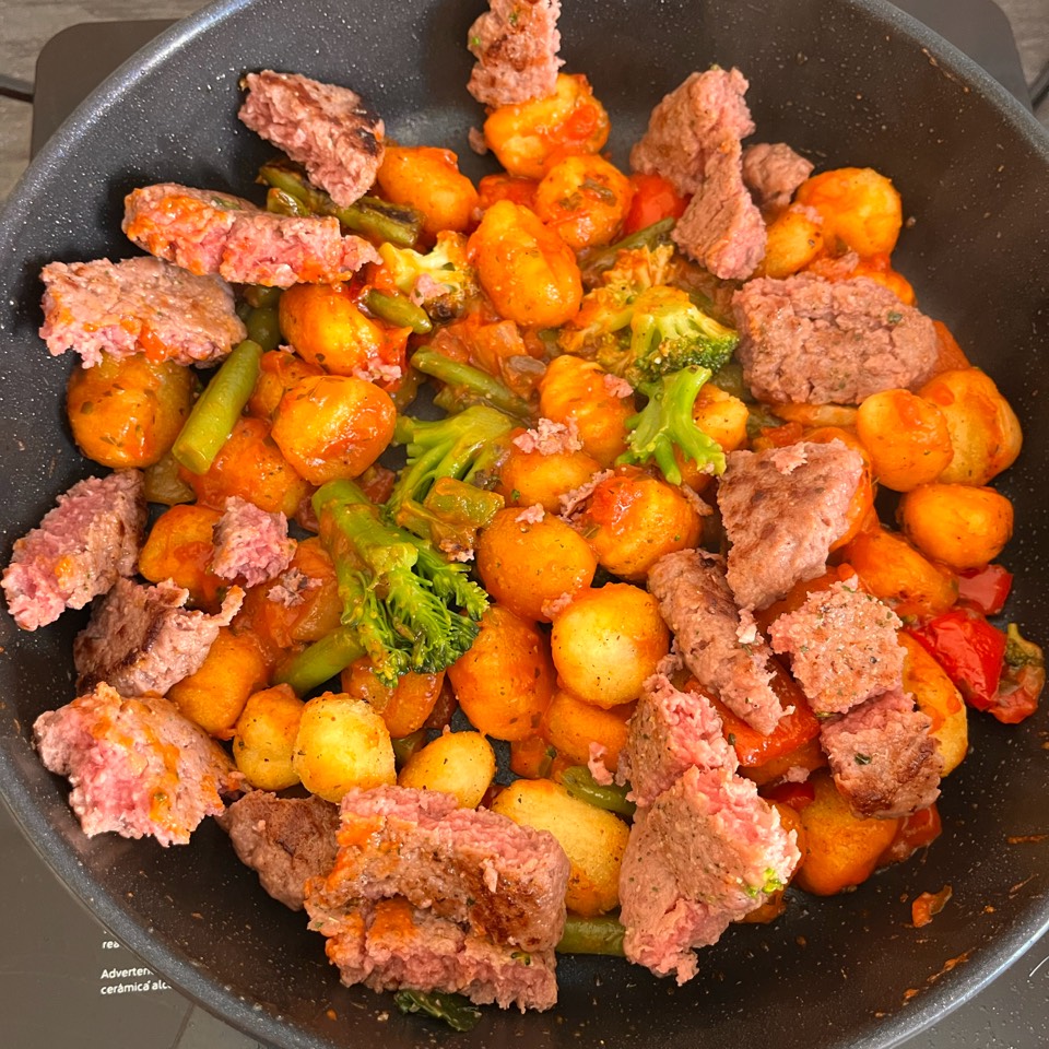 Gnochis con burguer de ternera troceada y verdura salteada con salsa de tomate y albahaca