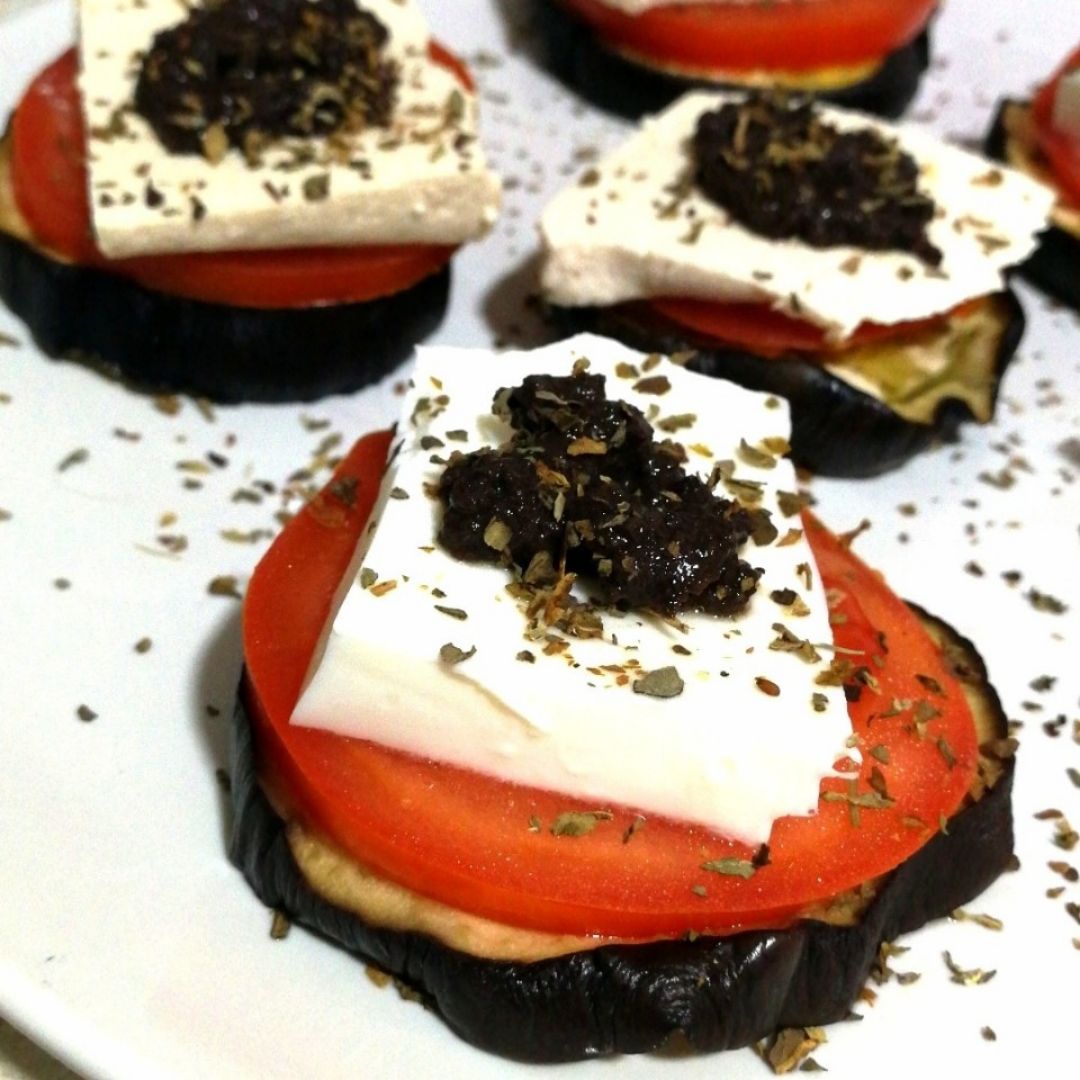 Timbal de berenjena, tomate y queso fresco/Tofu, coronado con un toque de olivada Timbal de berenjena, tomate y queso fresco/Tofu, coronado con un toque de olivada