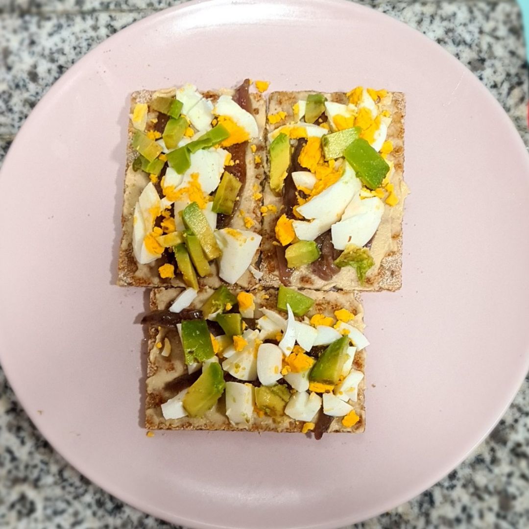 Tostas de sésamo con aguacate, huevo y anchoas.