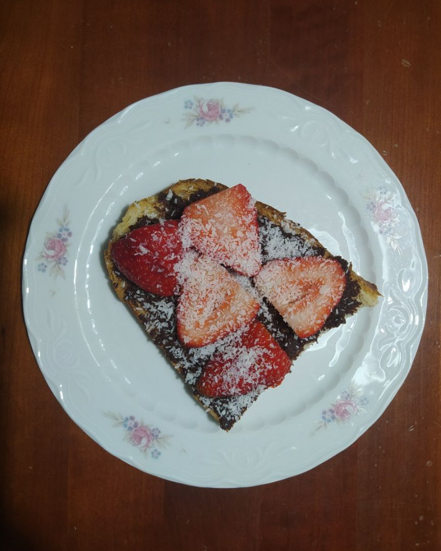 Tostada con crema de chocolate y avellanas, fresas y coco rayado Tostada con crema de chocolate y avellanas, fresas y coco rayado