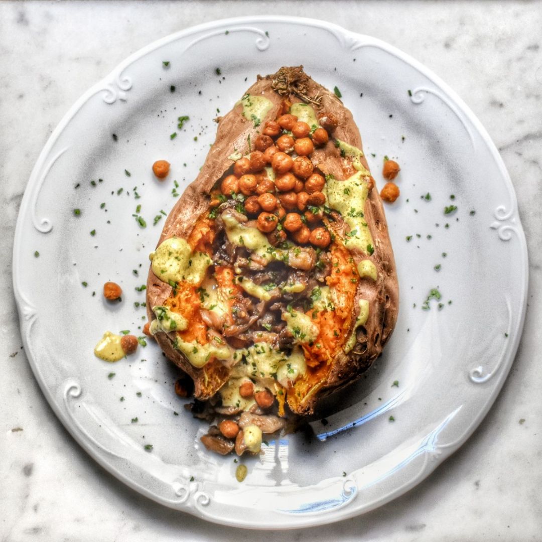 Boniato asado relleno de setas, con garbanzos crujientes especiados y salsa de curry y ajo Boniato asado relleno de setas, con garbanzos crujientes especiados y salsa de curry y ajo