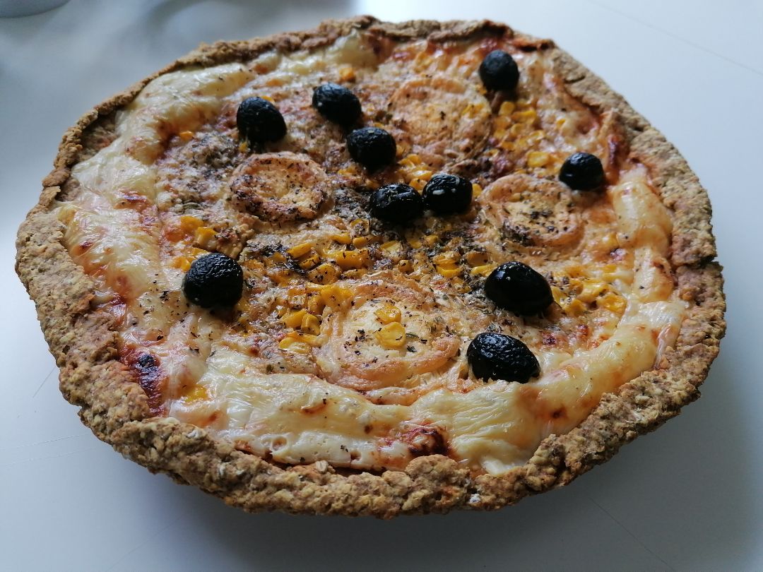 Pizza crujiente con base de copos de avena y toppings de distintos quesos, aceitunas negras y maíz Pizza crujiente con base de copos de avena y toppings de distintos quesos, aceitunas negras y maíz