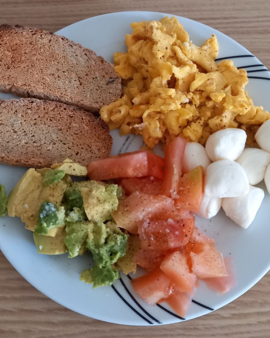 Tostadas y huevos revueltos con queso, tomate y aguacate
