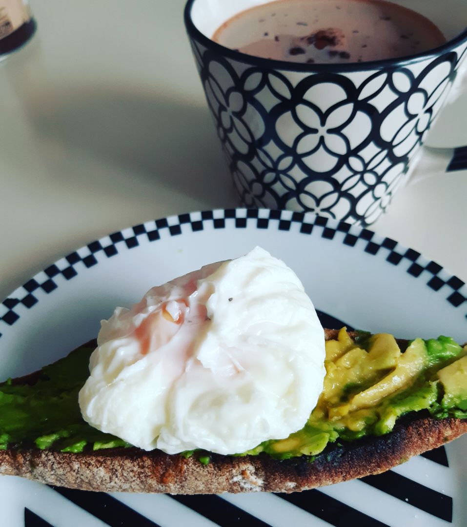 Pan con aguacate y huevo poché acompañado de bebida con cacao