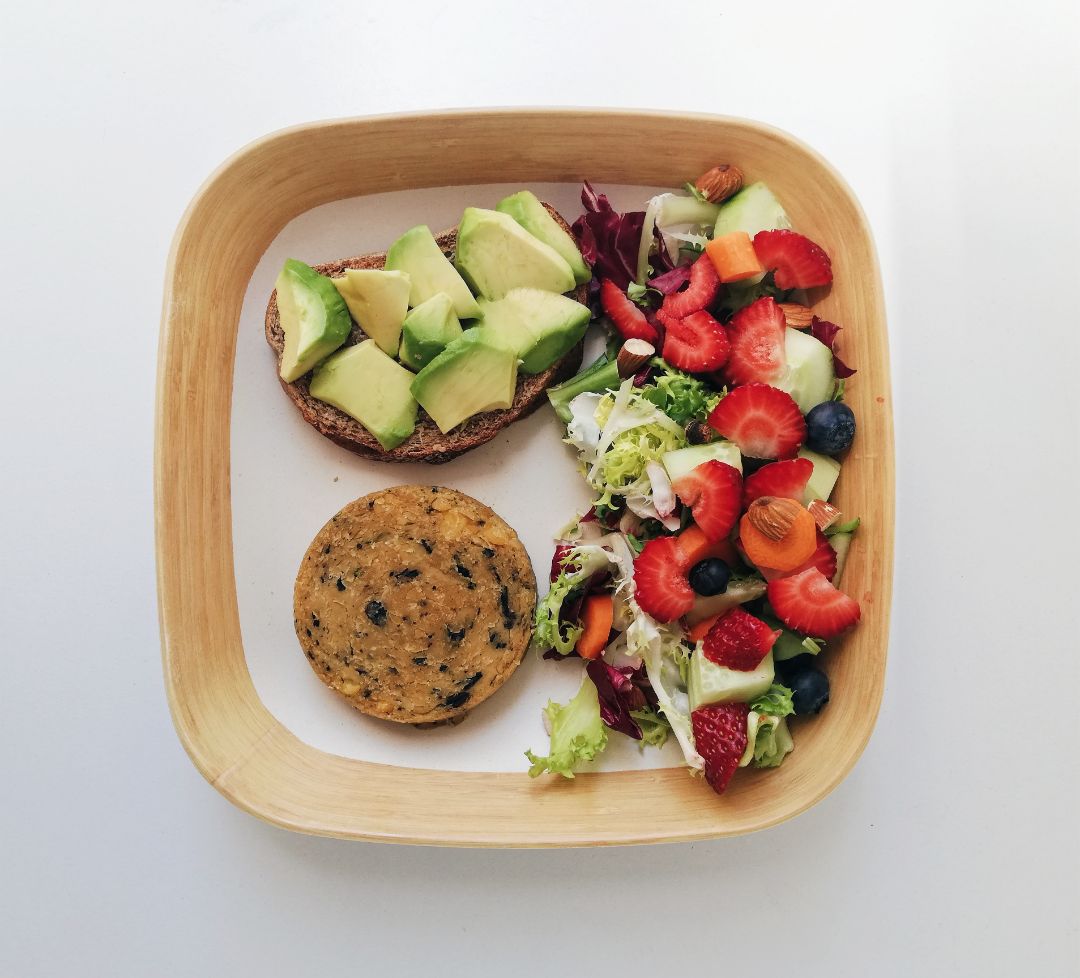 Plato combinado con ensalada, tostada de aguacate y hamburguesa vegetal