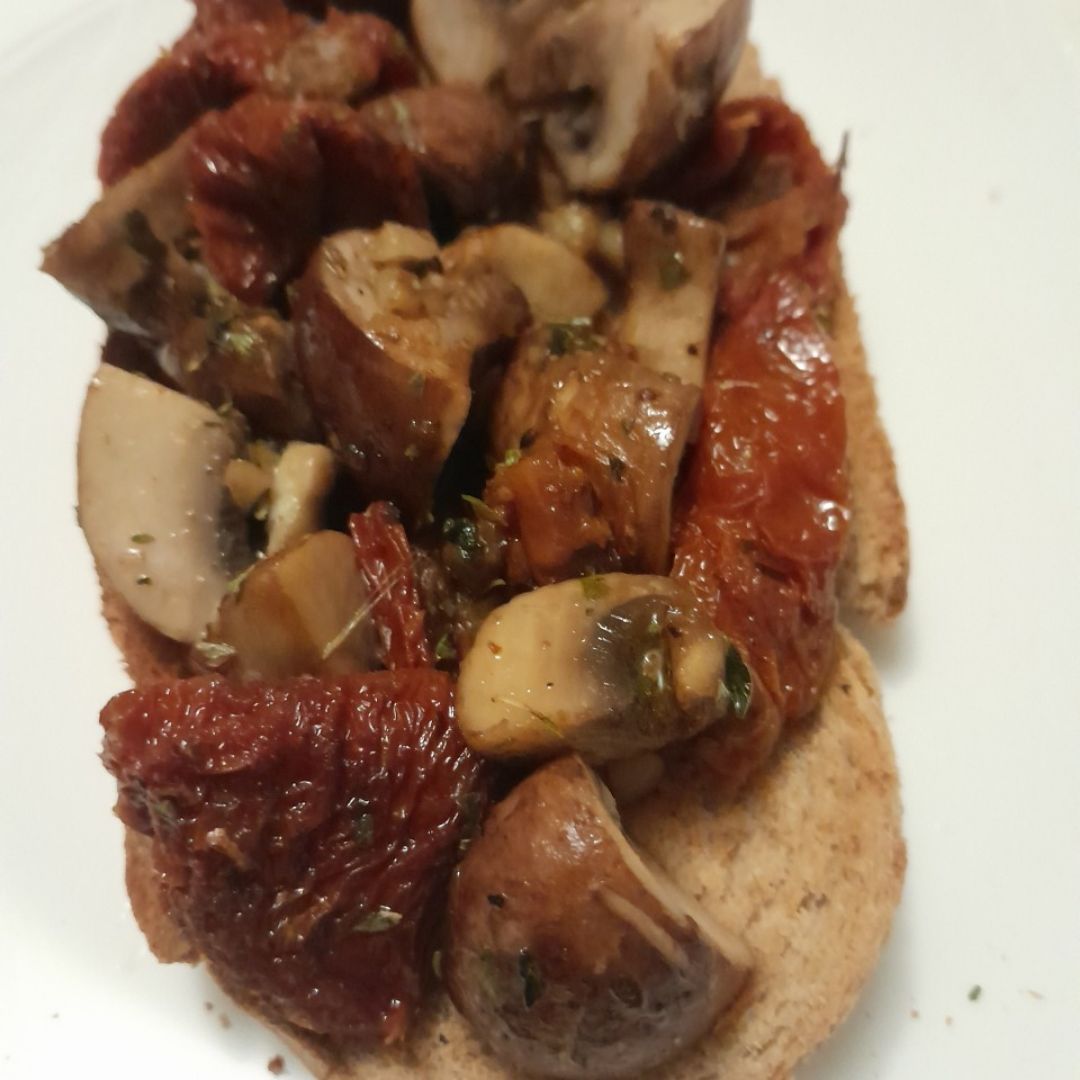 Tostada de champiñones y tomates secos.