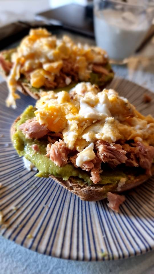 Tostada integral con aguacate, atún y huevo revuelto.