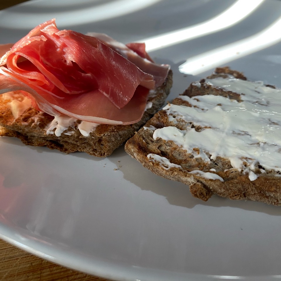 Tostada integral con queso suave y jamón serrano