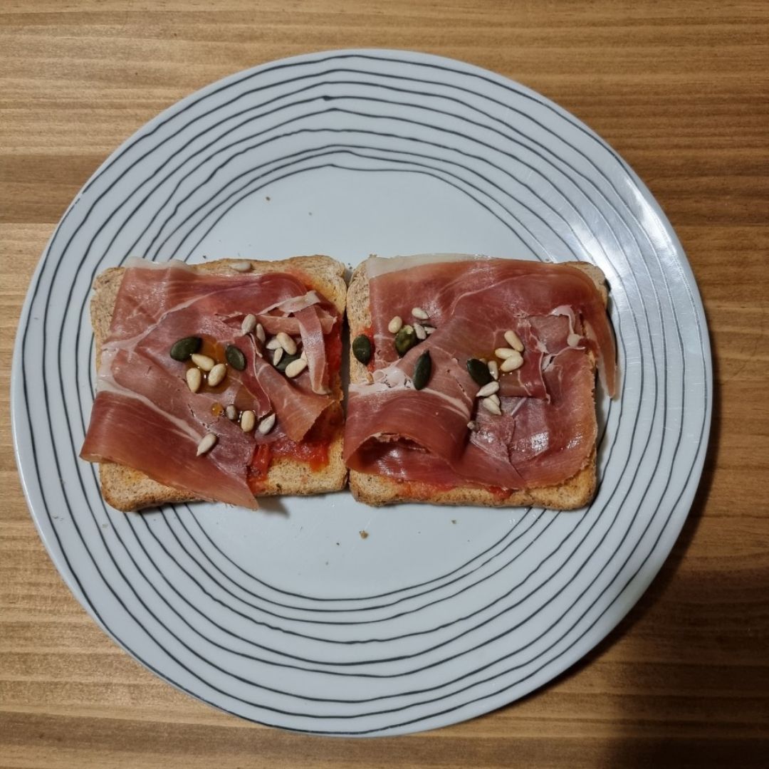 Tostas integrales con tomate triturado, jamón serrano y pipas Tostas integrales con tomate triturado, jamón serrano y pipas