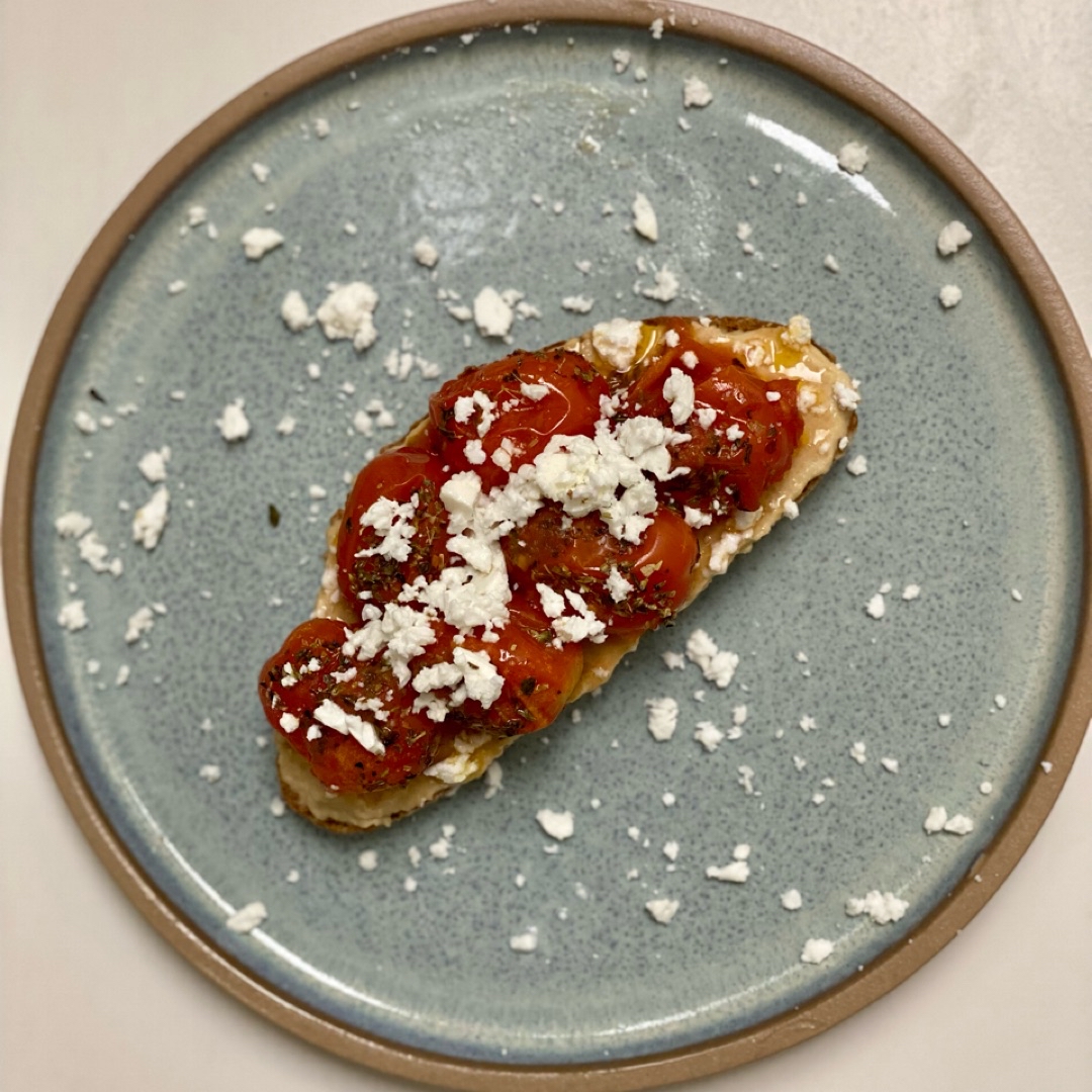 Tostada integral con hummus, cherrys asados y queso feta Tostada integral con hummus, cherrys asados y queso feta