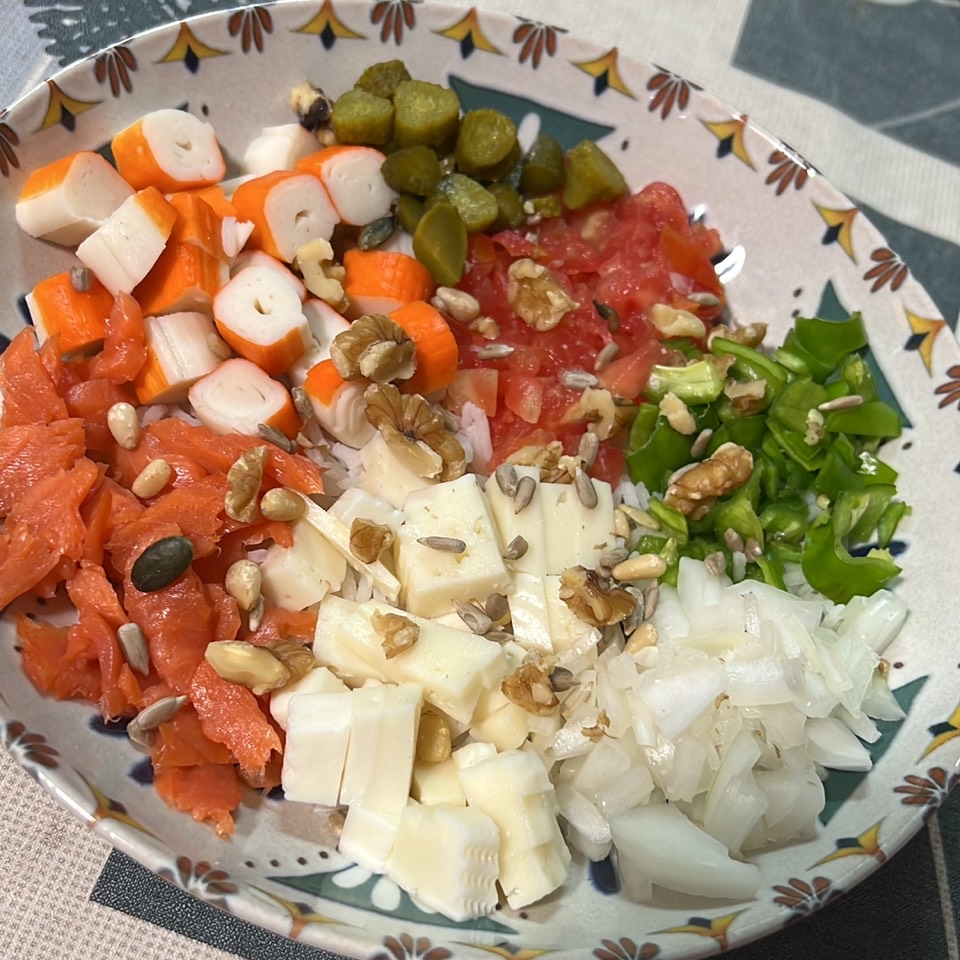 Ensalada de salmón con tomate, pepinillos, queso de cabra, cebolla, pimiento verde, palitos de cangrejo y nueces 