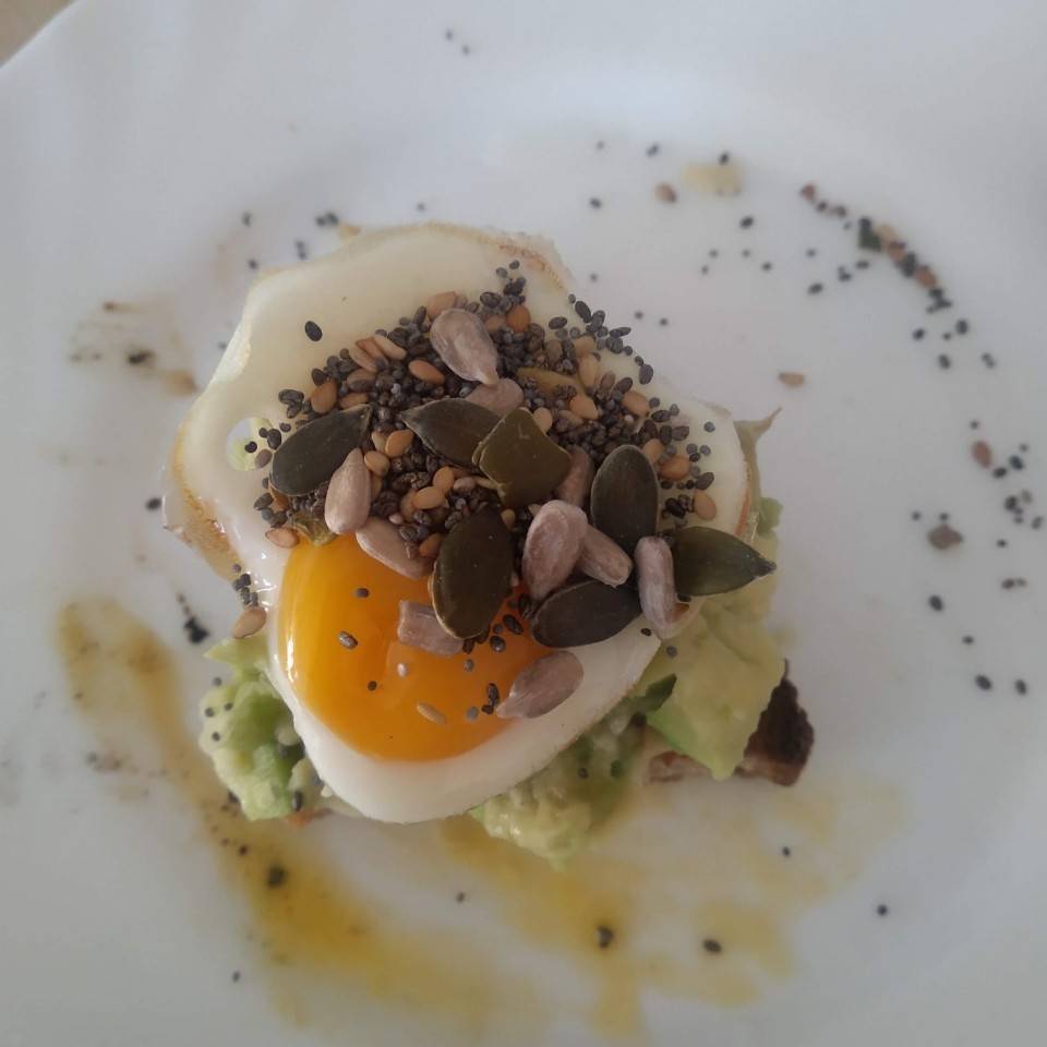 Tostada de ajo negro, aguacate y huevo de codorniz on semillitas