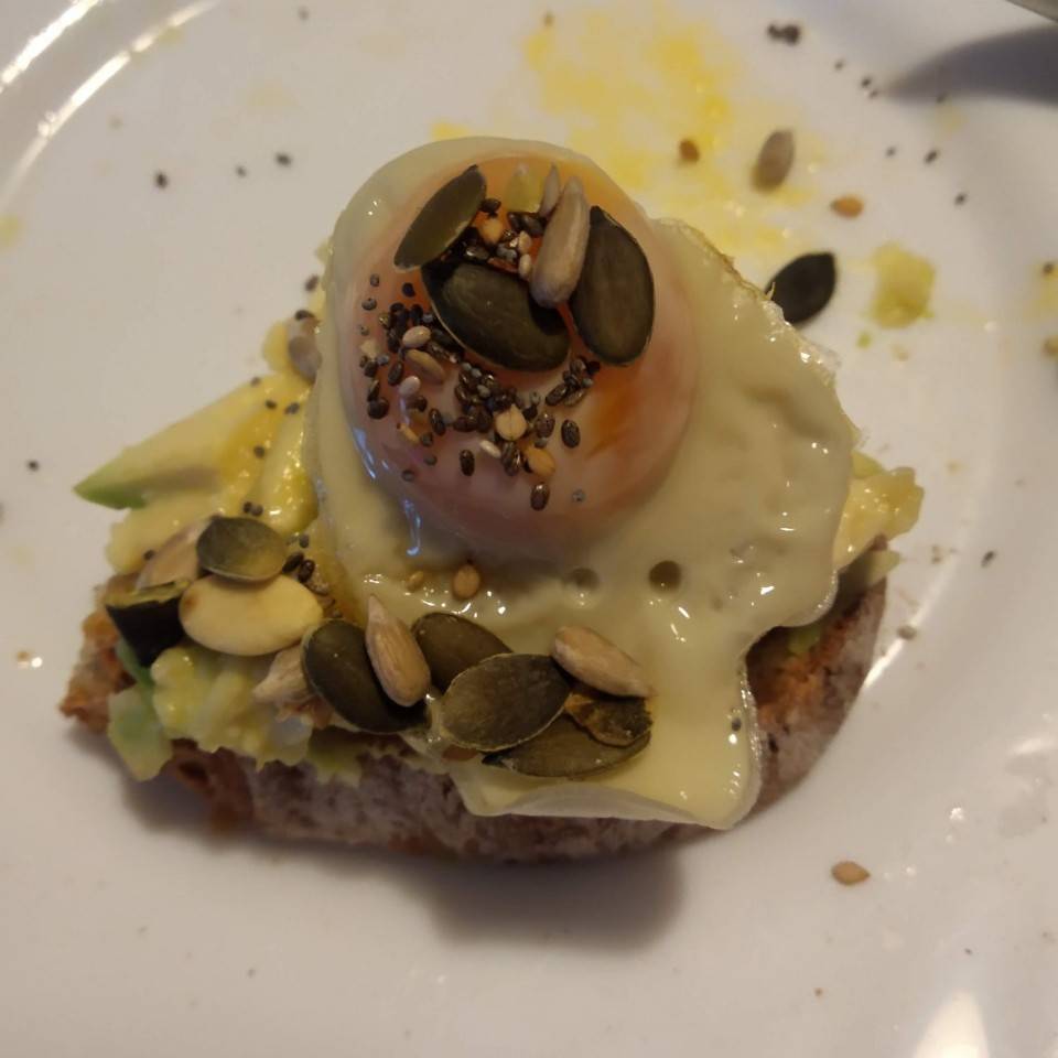Tostada de ajo negro, aguacate y huevo de codorniz on semillitas