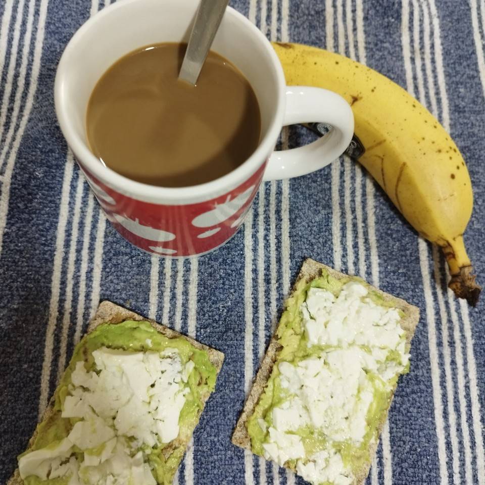 Café con leche, tostada de aguacate, queso y un plátano Café con leche, tostada de aguacate, queso y un plátano