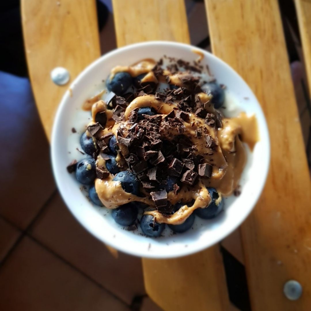 Bol de yogur natural con arándanos, crema de cacahuete y chocolate 85% Bol de yogur natural con arándanos, crema de cacahuete y chocolate 85%